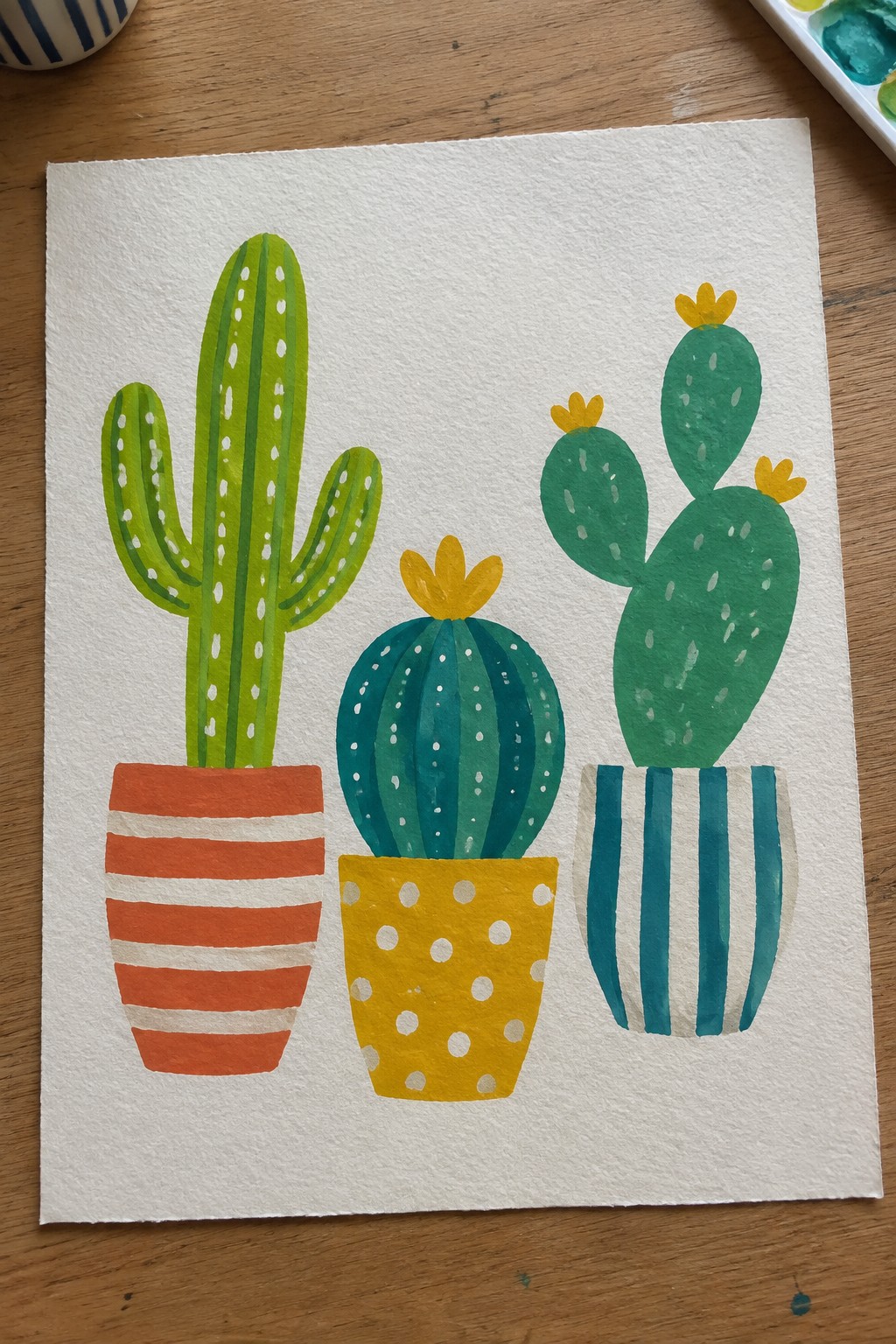 Watercolor painting of three cacti in red, yellow, and blue pots