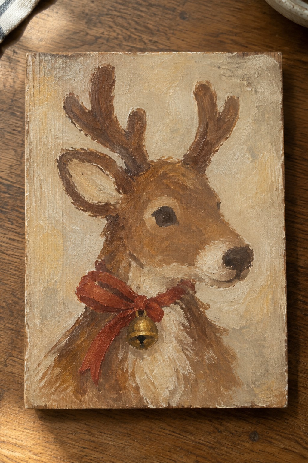 Rustic wooden plaque with painted reindeer head, red bow, and golden bell