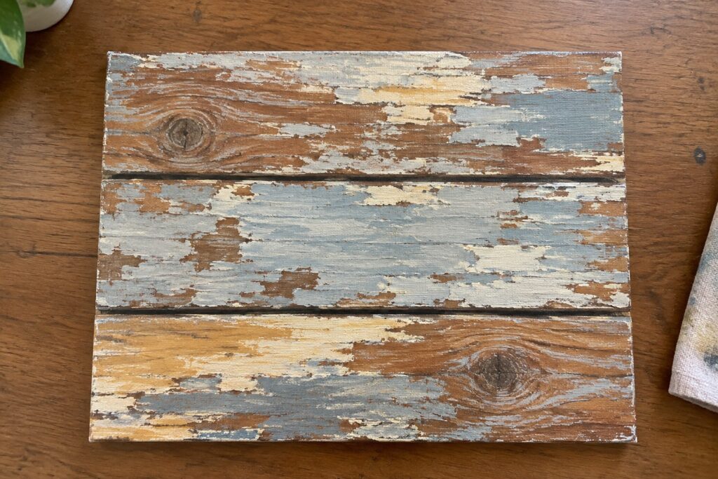 Distressed canvas mimicking three weathered wood planks with peeling white and gray paint