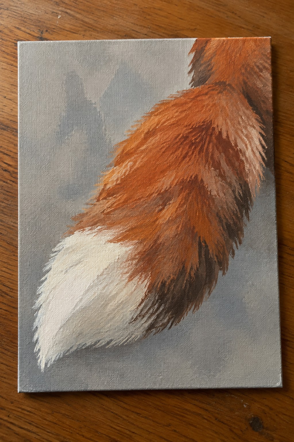 Painting of fluffy fox tail with orange fur and white tip on gray canvas