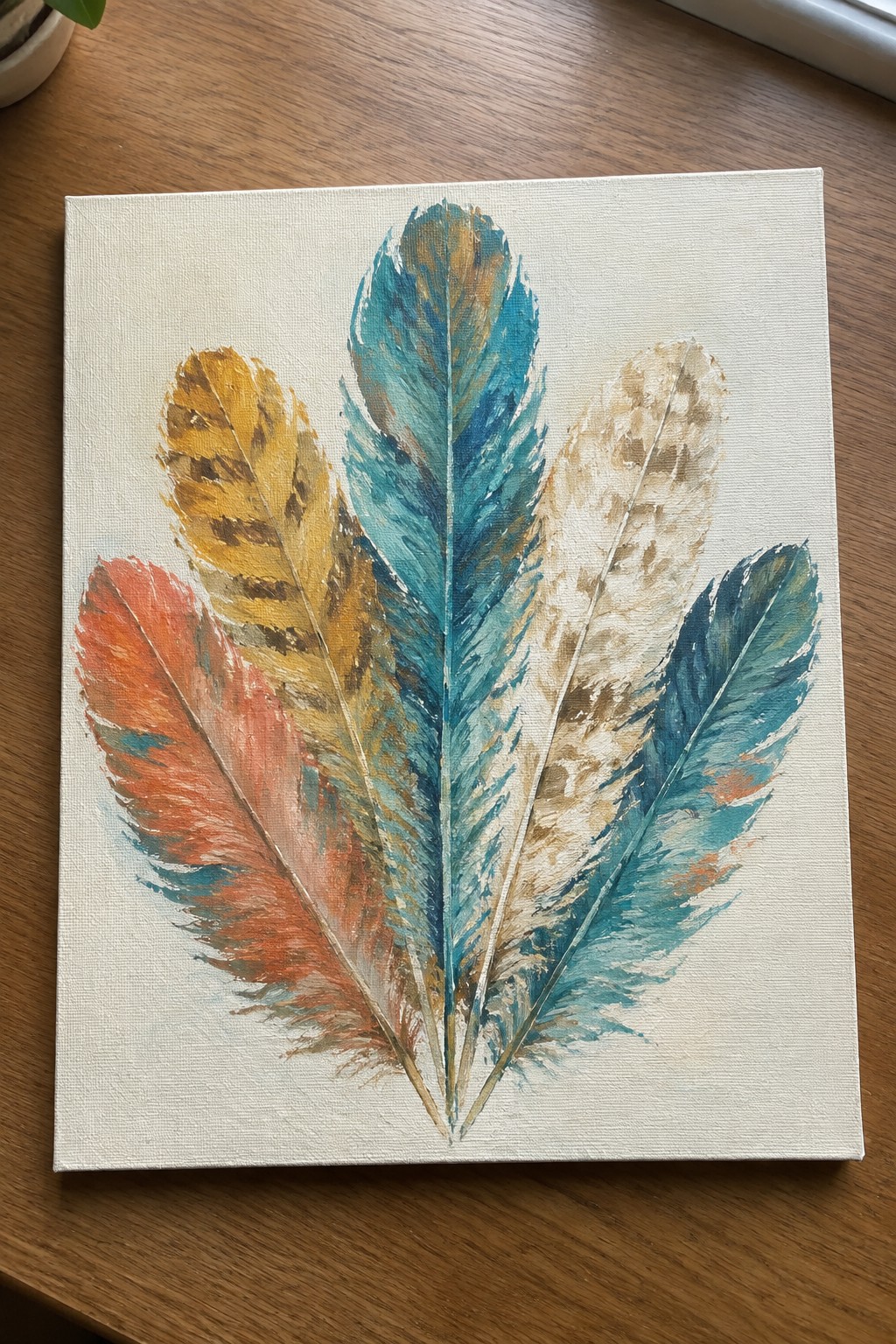 A canvas painting shows five overlapping feathers in orange, yellow, teal, and beige tones fanned out from a central point with visible dry brush strokes.