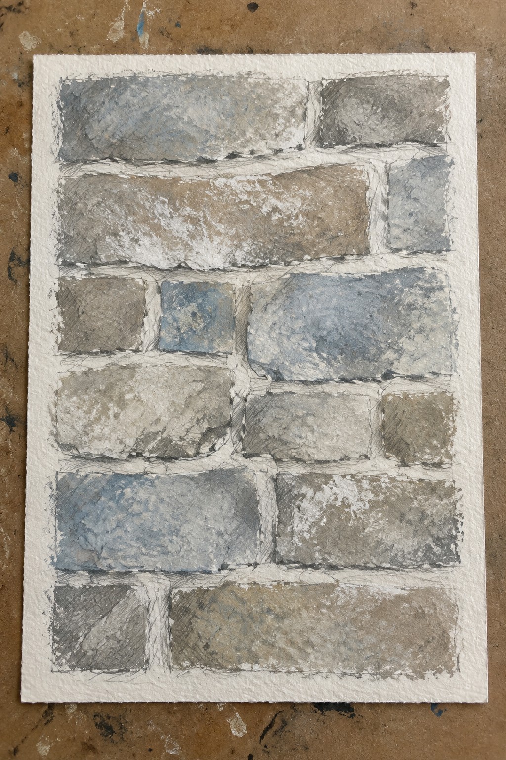 A watercolor painting of an irregular stone wall with gray, brown, and blue stones separated by white mortar lines on textured paper.