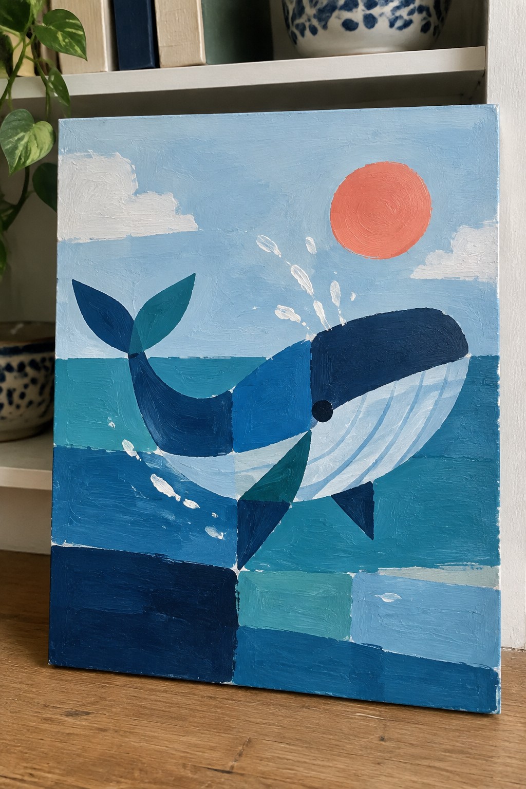 Geometric blue whale painting spouting water under red sun in blue sky