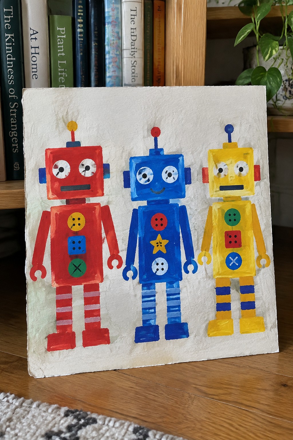 Three colorful painted robots in red, blue, and yellow on white canvas