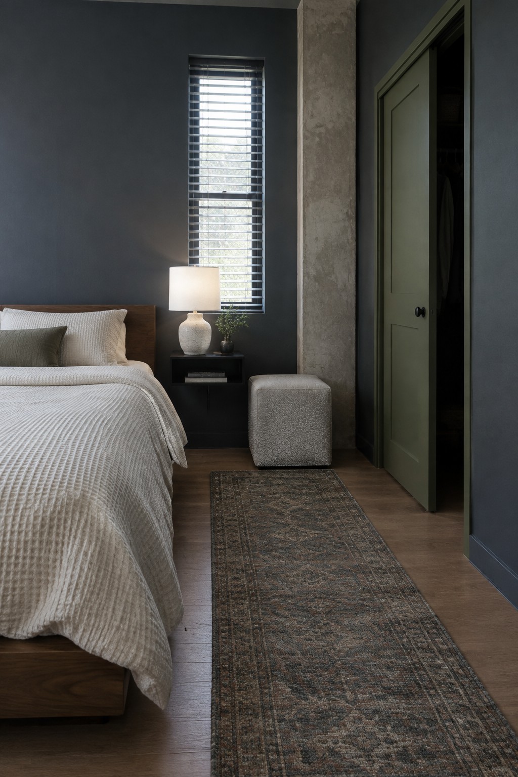 Dark gray bedroom with white bed, nightstand lamp, patterned rug, and open green door