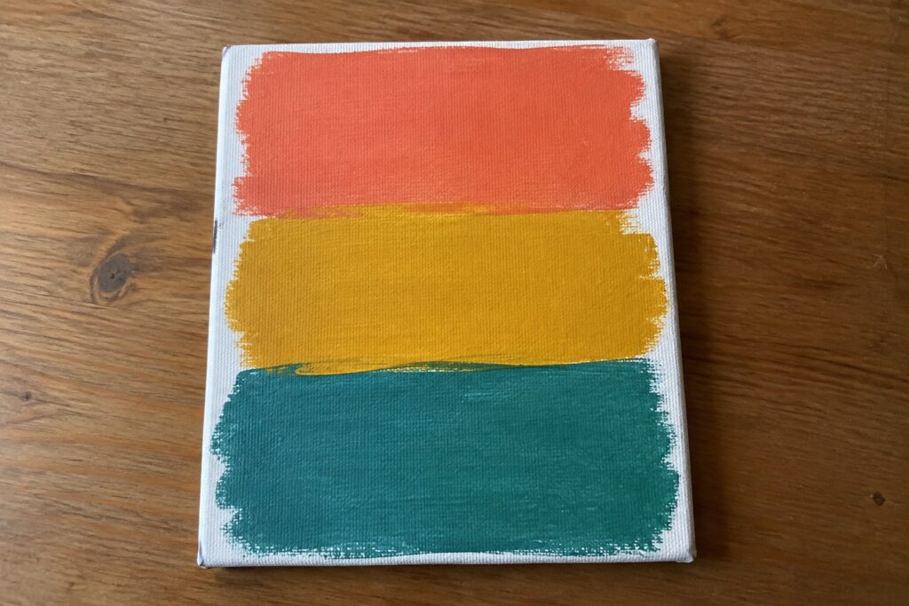 24 Simple Canvas Painting Ideas Without Complicated Sketching Abstract canvas with coral orange, yellow, and teal horizontal painted stripes on wood