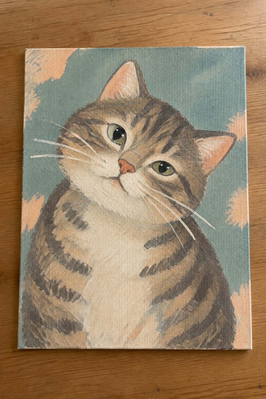 Tabby cat with green eyes painted on canvas against teal background