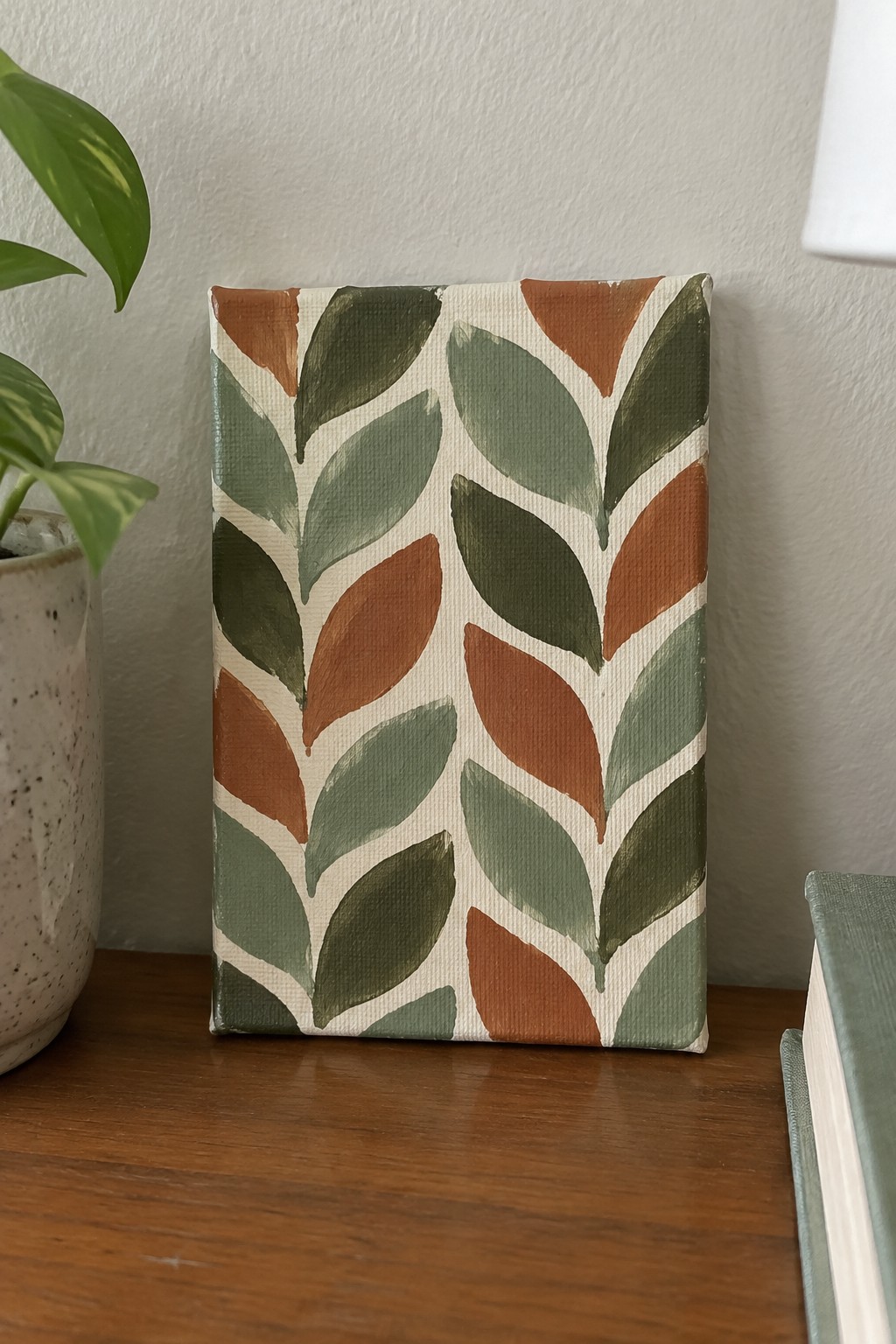 Abstract leaf pattern in green and terracotta on canvas atop wooden table