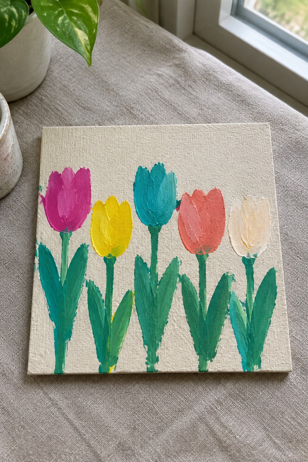 Colorful tulips painted on small canvas in pink, yellow, teal, coral and white.